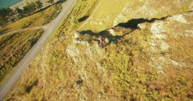 Genç yürüyüş adam uçurumun üstünde ayakta çevresinde yörünge Radyal uçuş. Uzakta görünüyor.