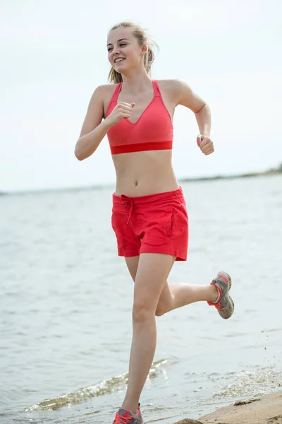 Young lady running at the sunny summer sand beach. Workout.  Jog