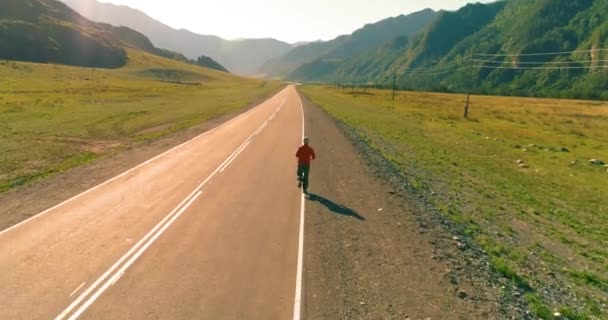 完璧なアスファルトの道路でスポーティな男の背後にある低空飛行 — ストック動画