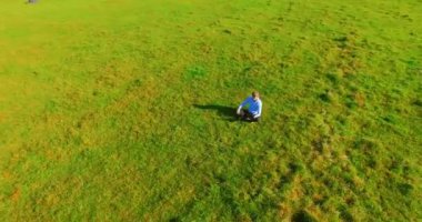 UHD 4k havadan görünümü. Defter pad ile yeşil çim sahasında oturan işadamı üzerinde düşük yörünge uçuş