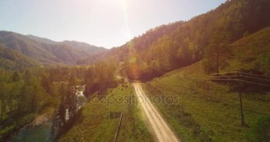 Taze dağ nehir ve çayır güneşli yaz sabahı, orta hava uçuş. Kırsal toprak yol aşağıda. İnek ve araba.