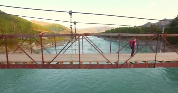 Mid-air flyvning over ung mand turist gå over en hængebro . – Stock-video