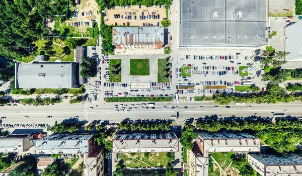 Vista aérea de la ciudad con encrucijadas y caminos, casas, edificios, parques y estacionamientos. Imagen panorámica soleada de verano —  Fotos de Stock