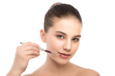 Temiz yüzü ile genç esmer kadın. Kız mükemmel cilt kozmetik fırça uygulamak. Beyaz izole.