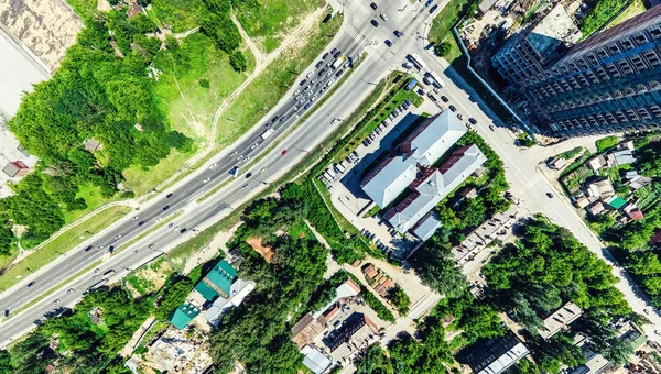 Aerial city view with crossroads and roads, houses, buildings, parks and parking lots. Sunny summer panoramic image