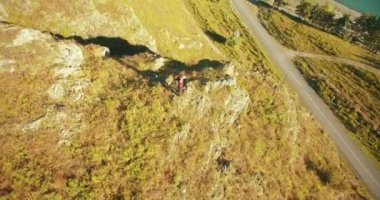 Genç yürüyüş adam uçurumun üstünde ayakta çevresinde yörünge Radyal uçuş. Uzakta görünüyor.