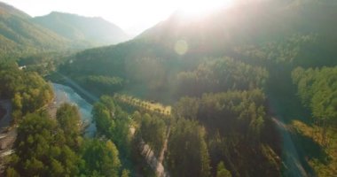 Güneşli yaz sabahında taze dağ nehri ve çayır üzerinde uçuşun ortasında. Aşağıdaki kırsal toprak yol.