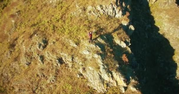 Orbital radial flight around young hiking man standing on top of the cliff. Hands up, winner — Stock Video