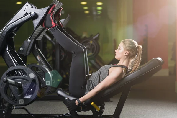 Sportive woman using weights press machine for legs. Gym. — Stock Photo, Image