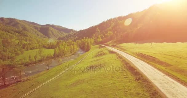 Mid air flygning över färska berg flod och äng på solig sommarmorgon. Landsbygdsvägen nedanför. — Stockvideo