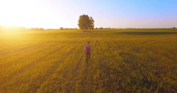 UHD 4K vista aérea. Vuelo de baja altitud frente a una mujer deportiva en el campo rural — Vídeo de stock