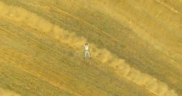 Luchtfoto. Verticale beweging vlucht over de mens liggend op gele tarweveld — Stockvideo