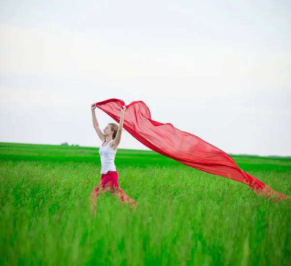 Jonge dame runing met weefsel in groene veld. Vrouw met sjaal. — Stockfoto