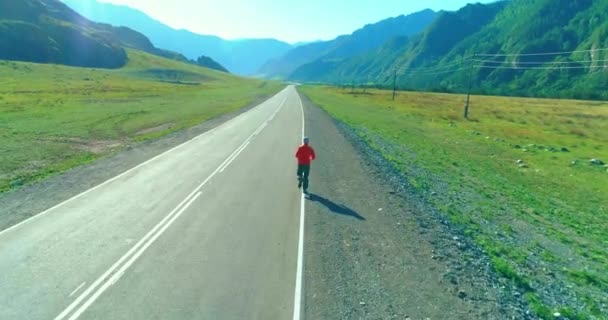 Vlucht van de lage hoogte achter van sportieve man op perfecte asfaltweg — Stockvideo