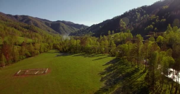 真夏の朝、新鮮な山の川や牧草地を上空で空中飛行します。下の未舗装道路. — ストック動画