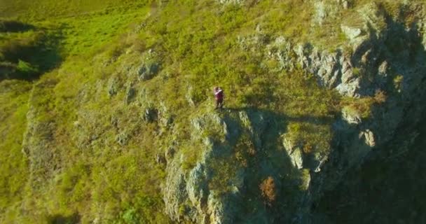 Orbitális sugárirányú repülés körül gyalogos fiatalember, egy szikla tetején áll. Úgy néz ki, el. — Stock videók