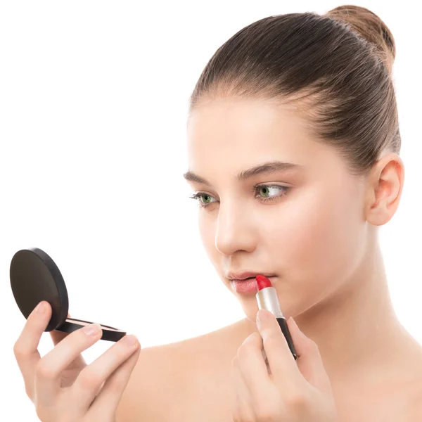 Giovane donna bruna con viso pulito perfetto applicare il rossetto usando lo specchio. Isolato su un bianco . — Foto Stock