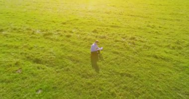 UHD 4k havadan görünümü. Defter pad ile yeşil çim sahasında oturan işadamı üzerinde düşük yörünge uçuş