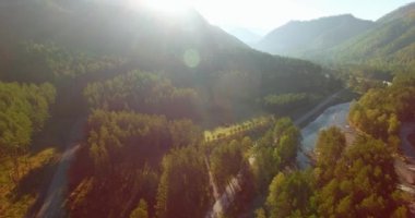 Güneşli yaz sabahında taze dağ nehri ve çayır üzerinde uçuşun ortasında. Aşağıdaki kırsal toprak yol.