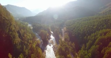 Güneşli yaz sabahında taze dağ nehri ve çayır üzerinde uçuşun ortasında. Aşağıdaki kırsal toprak yol.