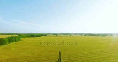 Yüksek voltajlı elektrik kulesi ve yeşil ve sarı alandaki elektrik hatları yakınında dikey hareket.