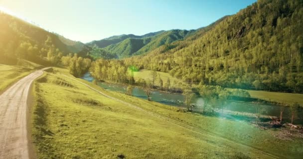 UHD 4K vue aérienne. Vol à basse altitude au-dessus d'une rivière de montagne fraîche et froide, prairie et route au matin ensoleillé d'été . — Video