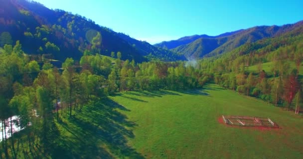 Volo a mezz'aria sul fiume fresco di montagna e prato al mattino d'estate soleggiato. Strada sterrata rurale sotto. — Video Stock