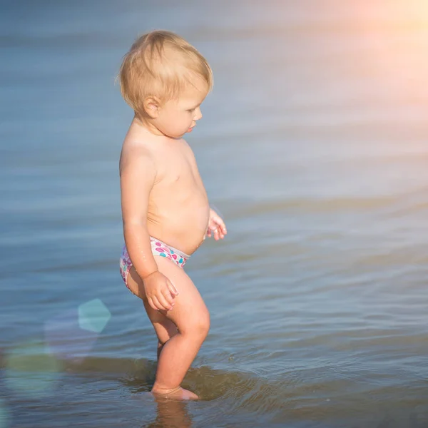 Carino bambino che gioca sulla spiaggia di sabbia e in acqua di mare . — Foto Stock