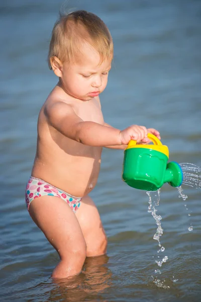 Carino bambino che gioca sulla spiaggia di sabbia e in acqua di mare . — Foto Stock