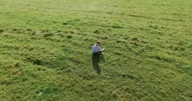 UHD 4k havadan görünümü. Defter pad ile yeşil çim sahasında oturan işadamı üzerinde düşük yörünge uçuş