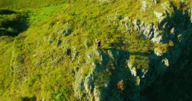 Genç yürüyüş adam uçurumun üstünde ayakta çevresinde yörünge Radyal uçuş. Uzakta görünüyor.