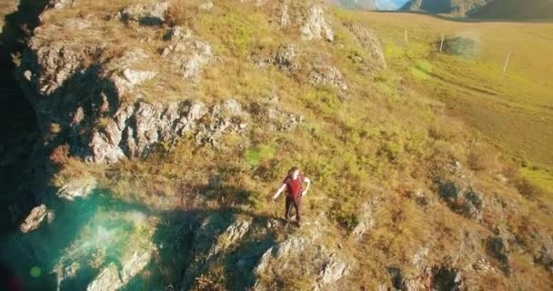 Aerial UHD 4K flight from young hiking man standing on top of the cliff — Stock Video