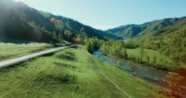 UHD 4k luchtfoto. Lage vlucht over verse koude berg rivier, weide en weg bij zonnige Zomerochtend. — Stockvideo