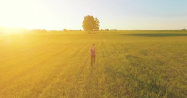 UHD 4K vista aérea. Vuelo de baja altitud frente a una mujer deportiva en el campo rural — Vídeos de Stock