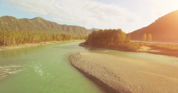 4k UHD vista aérea. Vôo baixo sobre o rio frio fresco da montanha na manhã ensolarada do verão. Árvores verdes e raios solares em horisont — Vídeo de Stock