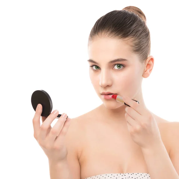 Junge brünette Frau mit perfekt sauberem Gesicht, die Lippenstift mit Spiegel aufträgt. isoliert auf einem weißen. — Stockfoto