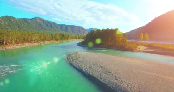 Vista aérea 4k UHD. Vuelo bajo sobre el río fresco de montaña fría en la soleada mañana de verano. Árboles verdes y rayos de sol en horisont — Vídeos de Stock