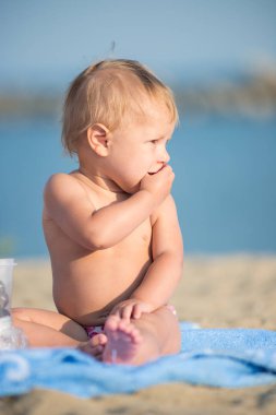 Şirin Bebek denize yakın kum plajındaki oyuncaklar ile oynama.