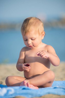 Şirin Bebek denize yakın kum plajındaki oyuncaklar ile oynama.