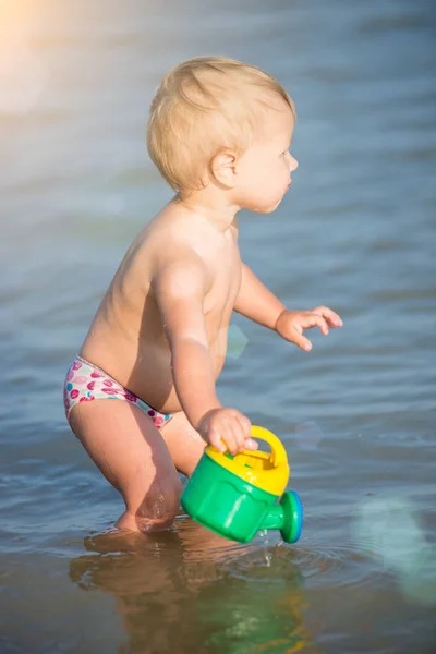 Lindo bebé jugando en la playa de arena y en agua de mar . — Foto de Stock