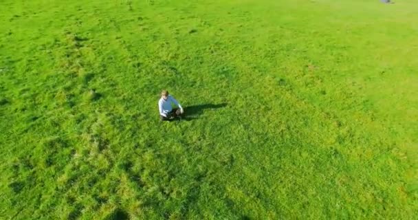 Uhd 4k légifelvételek. Alacsony Orbitális repülés alatt ül a zöld fű, notebook pad mező üzletember — Stock videók
