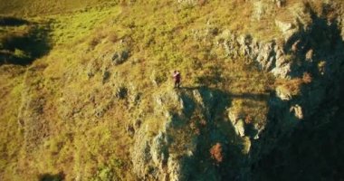 Genç yürüyüş adam uçurumun üstünde ayakta çevresinde yörünge Radyal uçuş. Uzakta görünüyor.