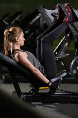 Bacaklar için ağırlıklar basın makine kullanan sportif kadın. Spor salonu.