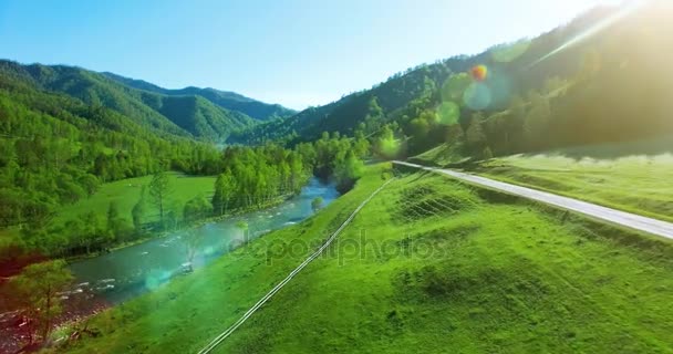 UHD 4K vista aérea. Vôo baixo sobre o rio frio fresco da montanha, o prado e a estrada na manhã ensolarada do verão . — Vídeo de Stock