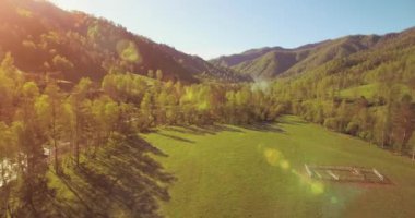 Güneşli yaz sabahında taze dağ nehri ve çayır üzerinde uçuşun ortasında. Aşağıdaki kırsal toprak yol.