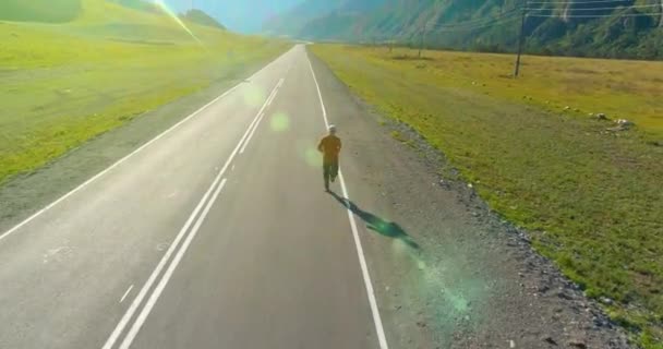 Voo de baixa altitude na frente do homem desportivo na estrada de asfalto perfeito — Vídeo de Stock