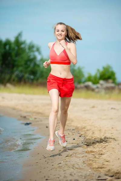 Jovencita corriendo en la soleada playa de arena de verano. Entrenamiento. Corre. —  Fotos de Stock