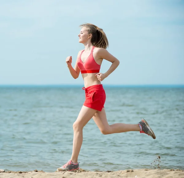 Giovane signora che corre alla soleggiata spiaggia di sabbia estiva. Allenati. Jogging — Foto Stock