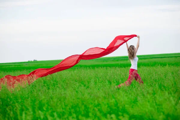 Jovencita corriendo con tejido en el campo verde. Mujer con bufanda . —  Fotos de Stock