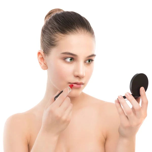 Jeune femme brune avec un visage propre parfait appliquant du rouge à lèvres à l'aide d'un miroir. Isolé sur un blanc . — Photo